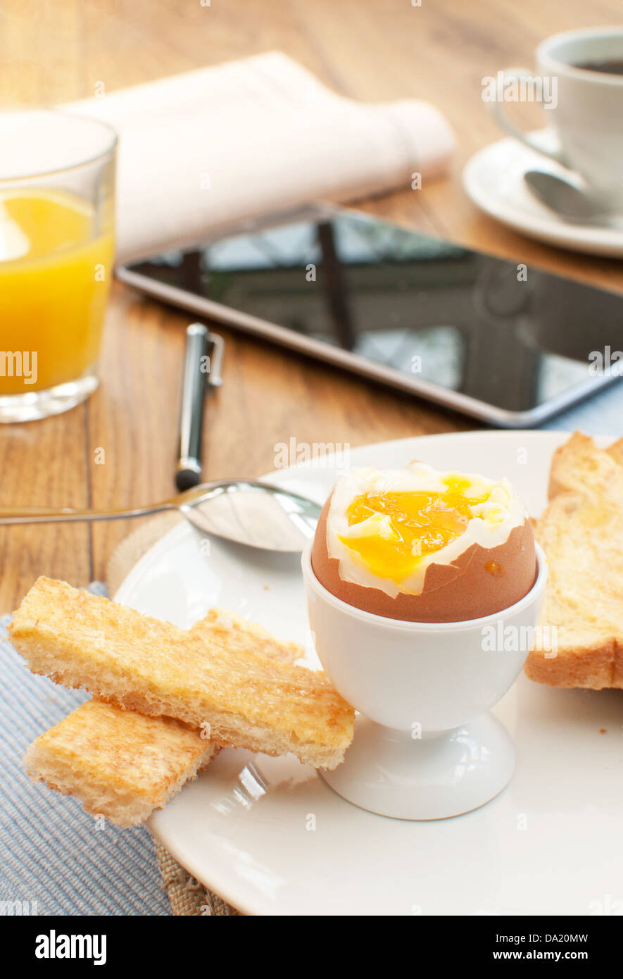 Oeuf mollet et toast avec une tablette et journaux Banque D'Images