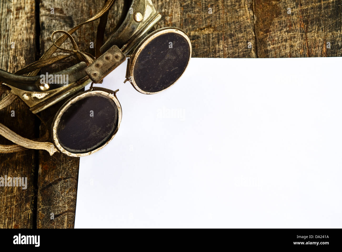 Lunettes de soudure ancienne et blanc papier blanc sur fond de bois. Banque D'Images
