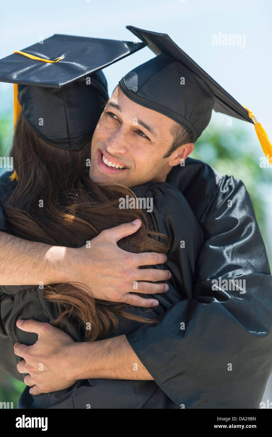 Les étudiants masculins et féminins embrassant sur la cérémonie de remise de diplômes Banque D'Images