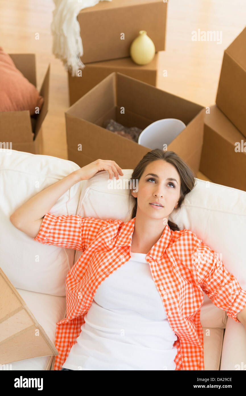 Jeune femme reposant sur canapé après le déménagement dans la nouvelle maison Banque D'Images