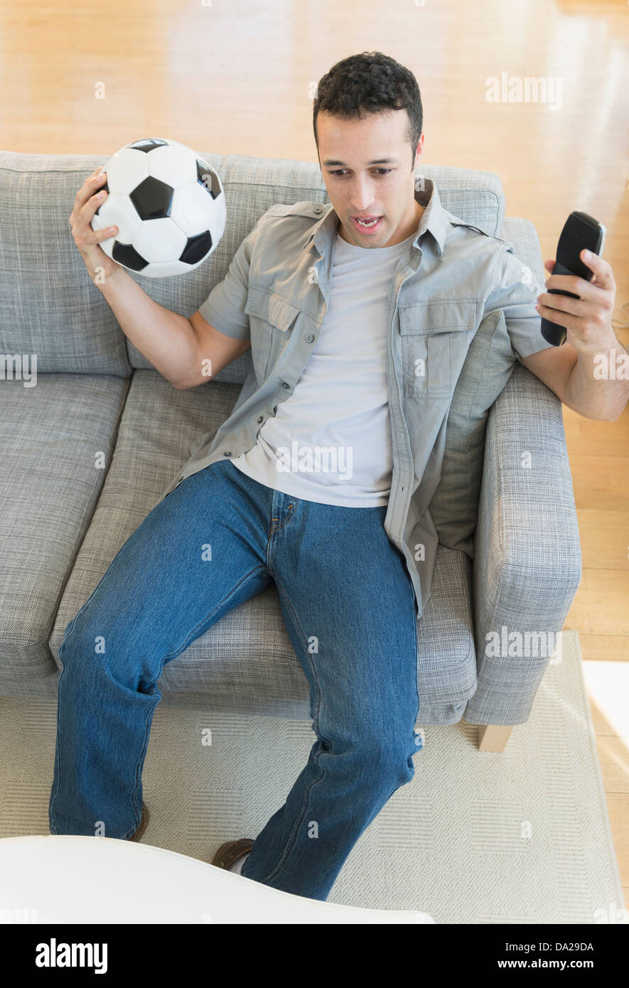 Jeune homme regarder match de football à la télévision Banque D'Images