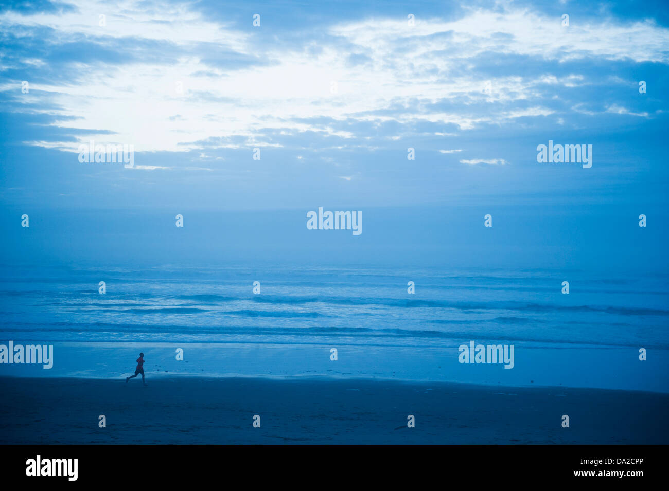USA, Ohio, Rockaway Beach, vue éloignée sur woman running along beach Banque D'Images