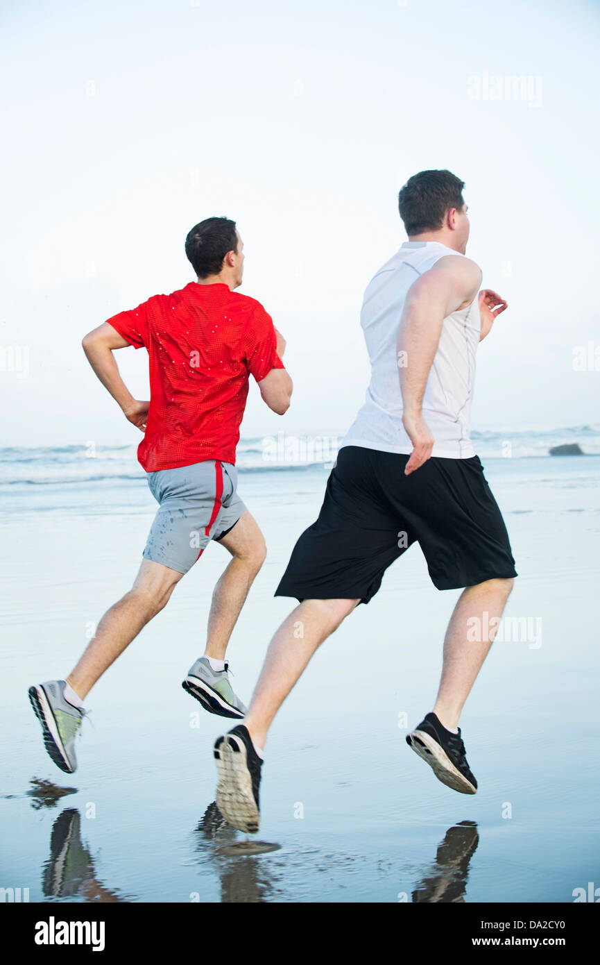 USA, Ohio, Rockaway Beach, les jeunes hommes adultes running on beach Banque D'Images