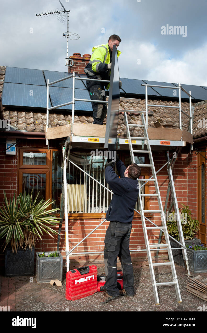 Les hommes en place de panneaux photovoltaïques de levage Banque D'Images