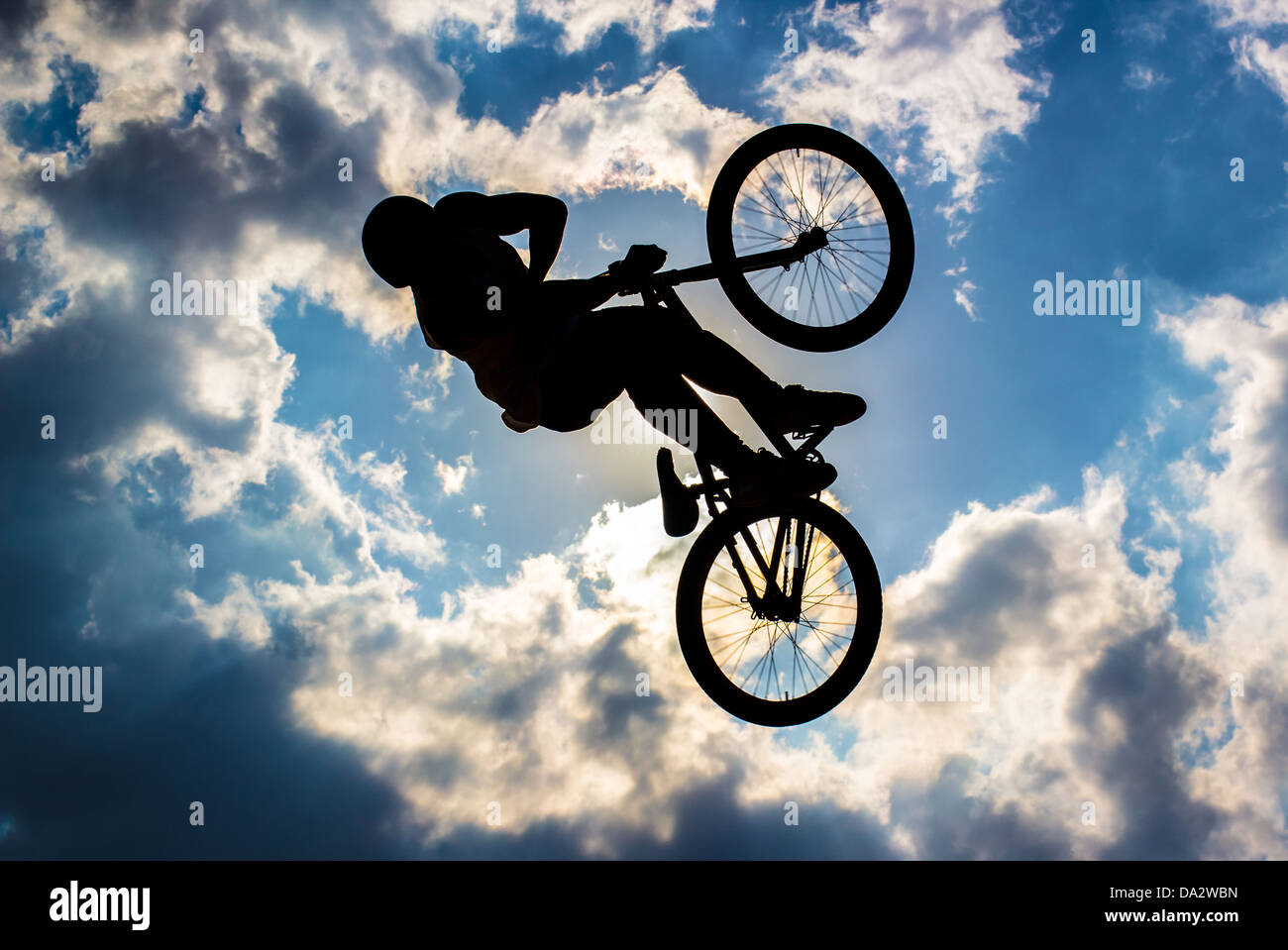 Silhouette d'un cycliste battant en arrière-plan le soleil et ciel bleu avec des nuages Banque D'Images