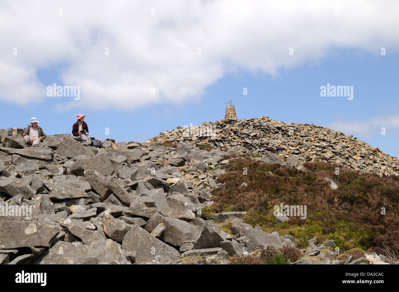 Couple assis près de Cairn et trig point sur le sommet de la montagne ou de l'EIFL a Riivals Gwynedd Llyn Peninsula Wales Cymru UK Banque D'Images