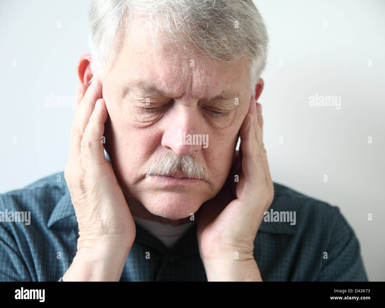 Homme plus âgé détient les deux mains à sa mâchoire supérieure près des oreilles Banque D'Images