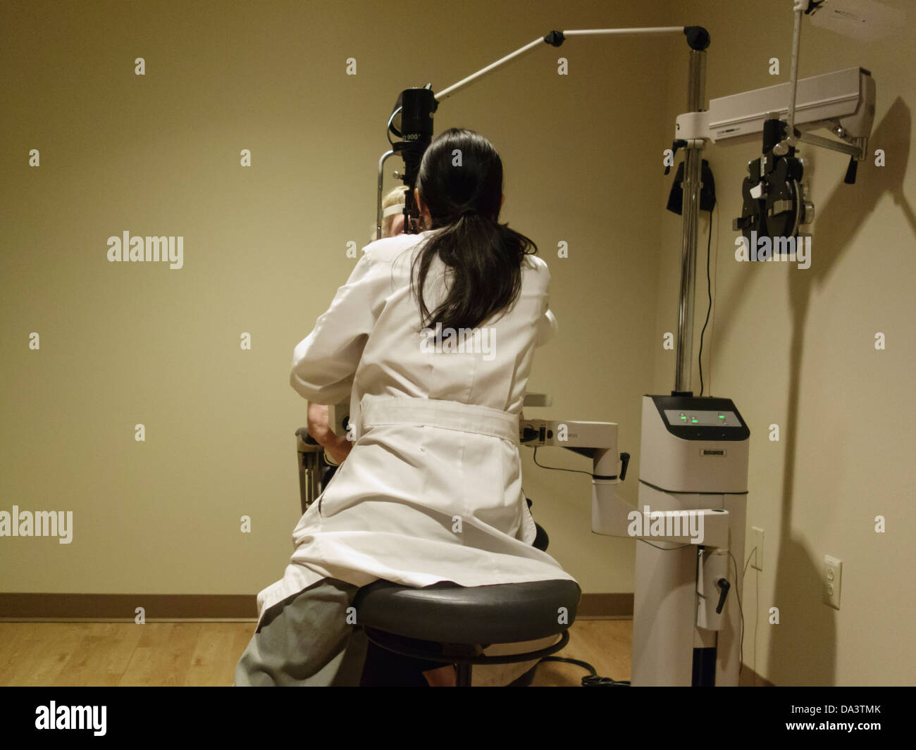 Une asiatique ophtalmologiste examine sous les yeux d'un 77 ans caucasien femme dans une salle d'examen. Oklahoma City, Oklahoma, USA. Banque D'Images