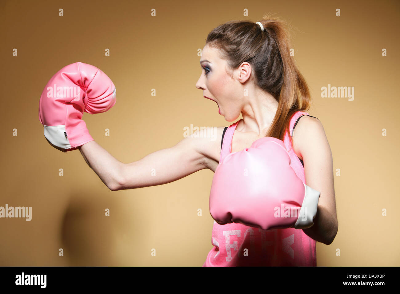Boxer model wearing big fun pink gloves jeu sport boxing studio shot, fond brun Banque D'Images