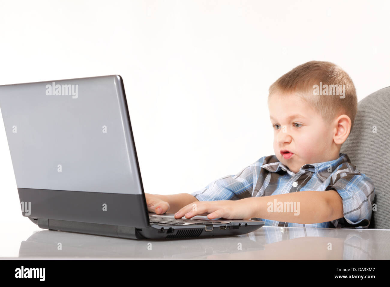 La dépendance de l'ordinateur de l'enfant garçon émotif avec ordinateur portable jeux portable isolé sur fond blanc Banque D'Images