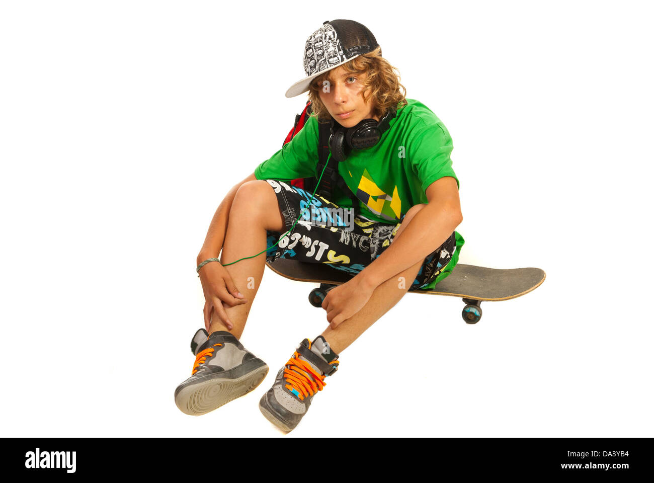 Teen boy sitting on skateboard isolé sur fond blanc Banque D'Images