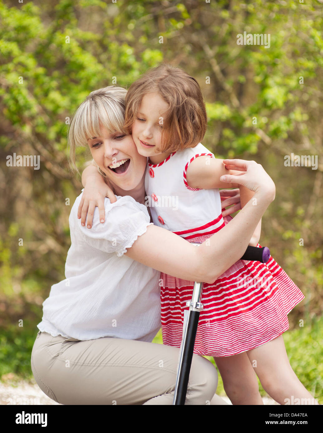 Mère et fille hug en parc avec scooter Banque D'Images