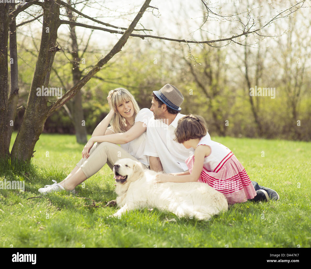 Family sitting in park with dog Banque D'Images