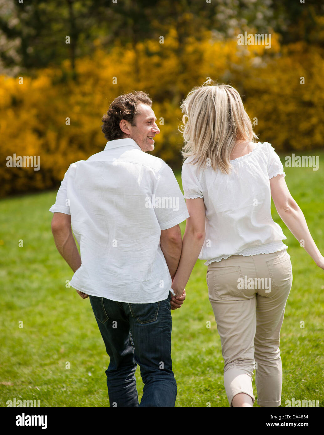 Couple retour à l'appareil photo en marche par park Banque D'Images