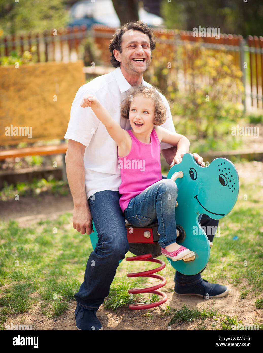 Père et fille sur l'aire de jeux sur ressort Banque D'Images