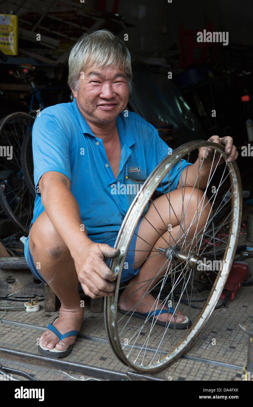 Portrait de l'homme travaillant sur des roues de vélo, Georgetown, Penang, Malaisie Banque D'Images