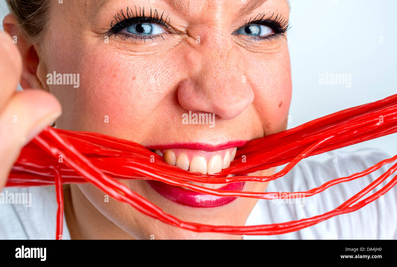 Une jeune femme de manger beaucoup de bonbons réglisse rouge dentelle Banque D'Images