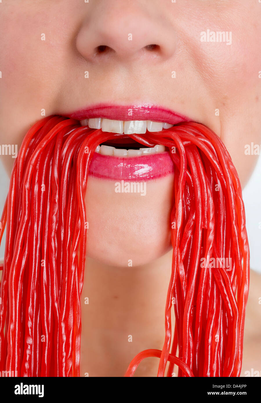 Un gros plan d'une bouche de femme de manger beaucoup de bonbons réglisse rouge dentelle Banque D'Images