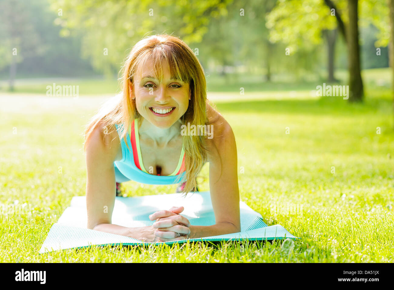 Forme physique femelle moniteur titulaire planche l'exercice à l'extérieur en vert parc d'été Banque D'Images