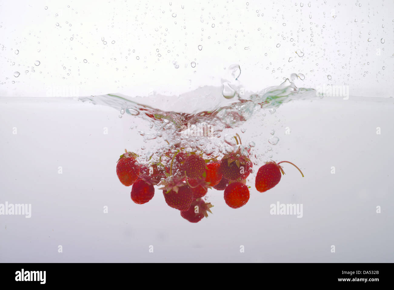 Les fraises dans l'eau éclaboussée Banque D'Images