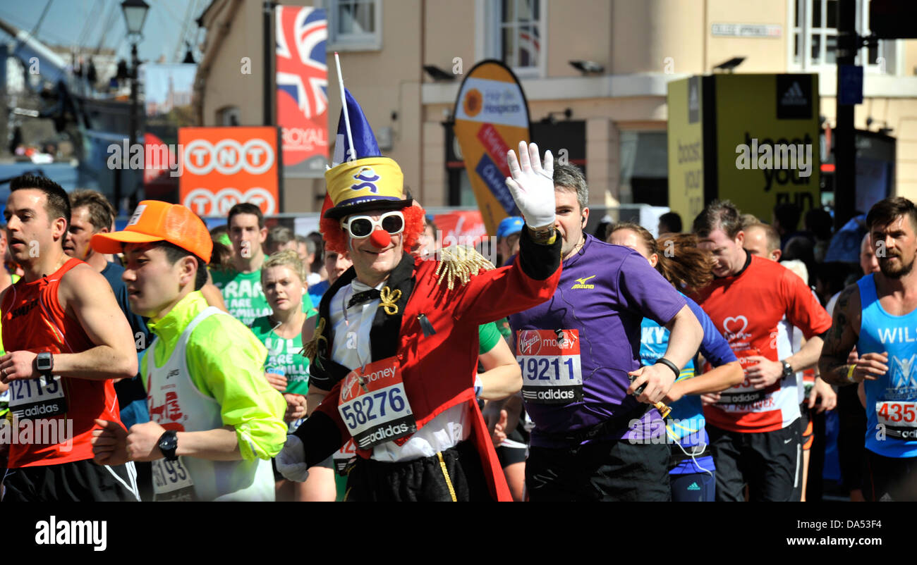 Runner habillé en clown au marathon de Londres des vagues à la foule au milieu d'une foule d'autres coureurs à Greenwich Banque D'Images
