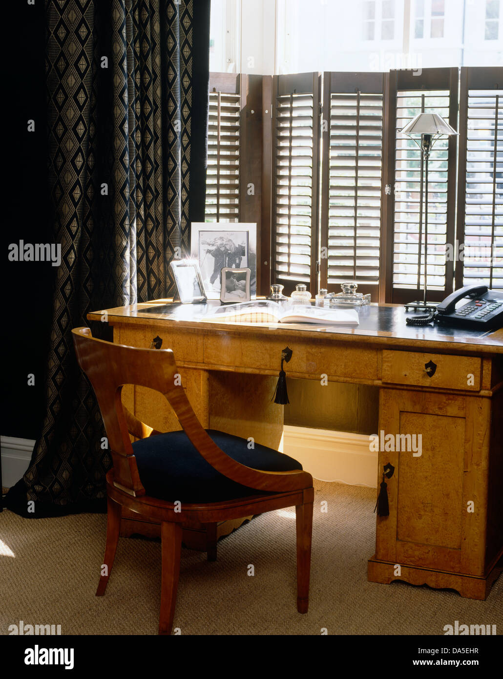 Présidence et bureau en face de fenêtre avec des volets et des rideaux sombres en étude masculin Banque D'Images