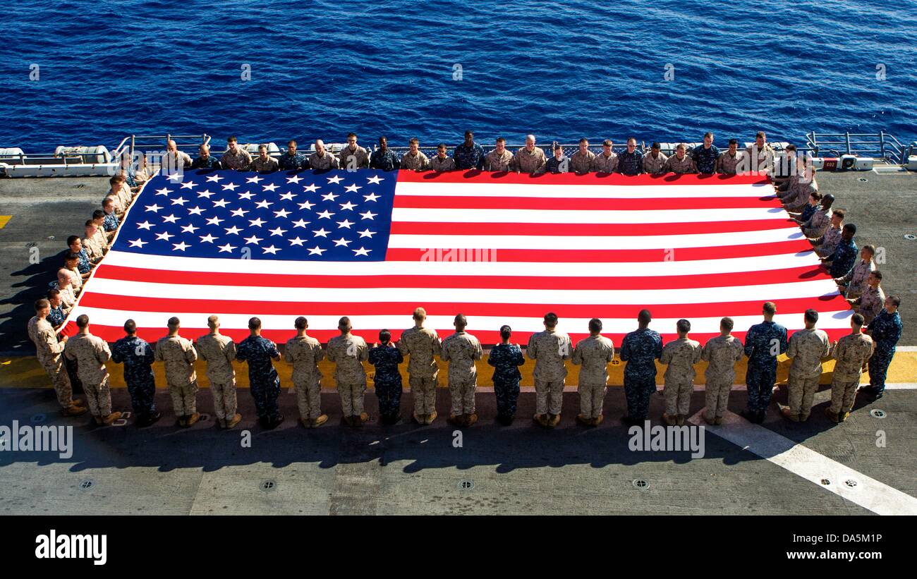 Les Marines américains et les marins tenir le drapeau américain pour commémorer le jour de l'indépendance dans le poste de pilotage de l'USS Kearsarge 4 juillet 2013 dans la mer Rouge. Banque D'Images