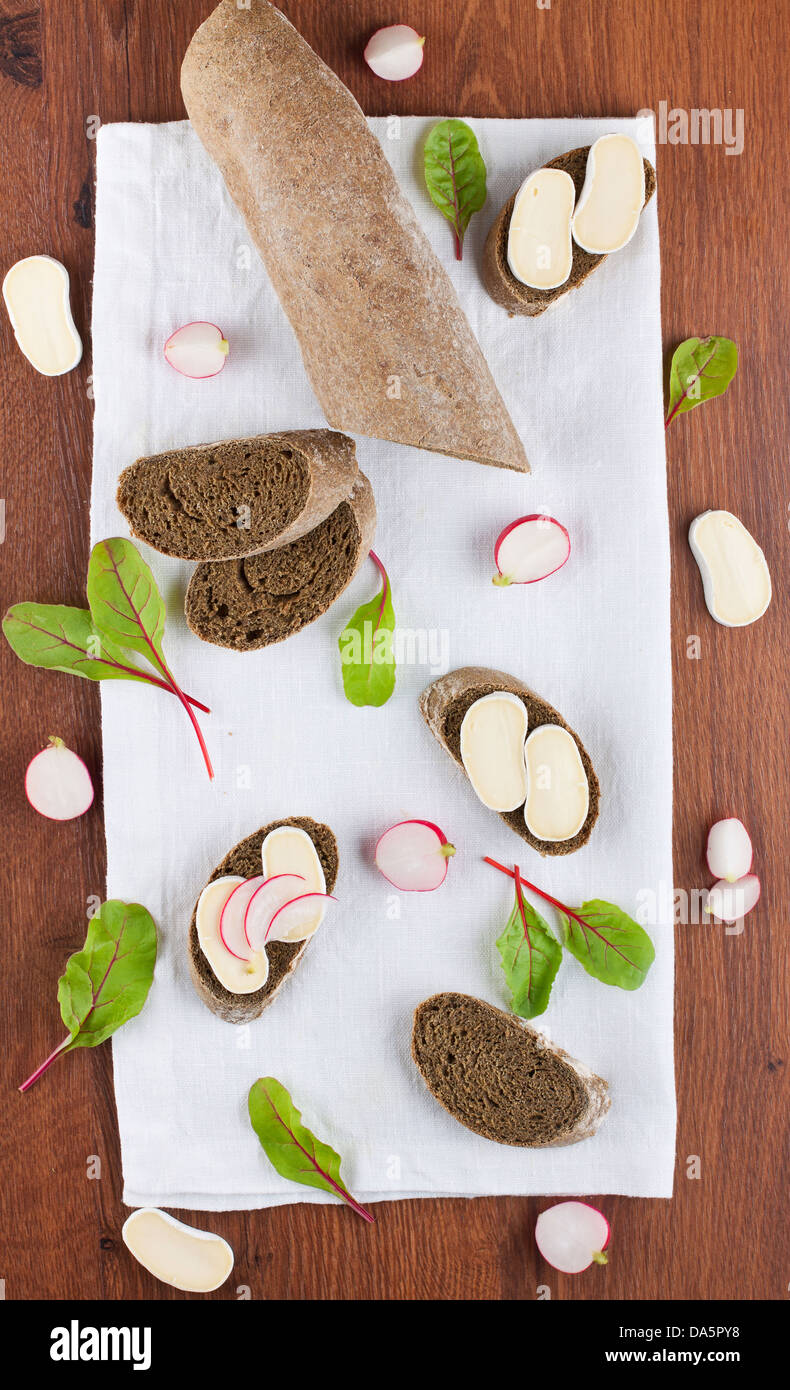 Baguette de seigle et de fromage doux canapés ornés de feuilles de salades et radis Banque D'Images