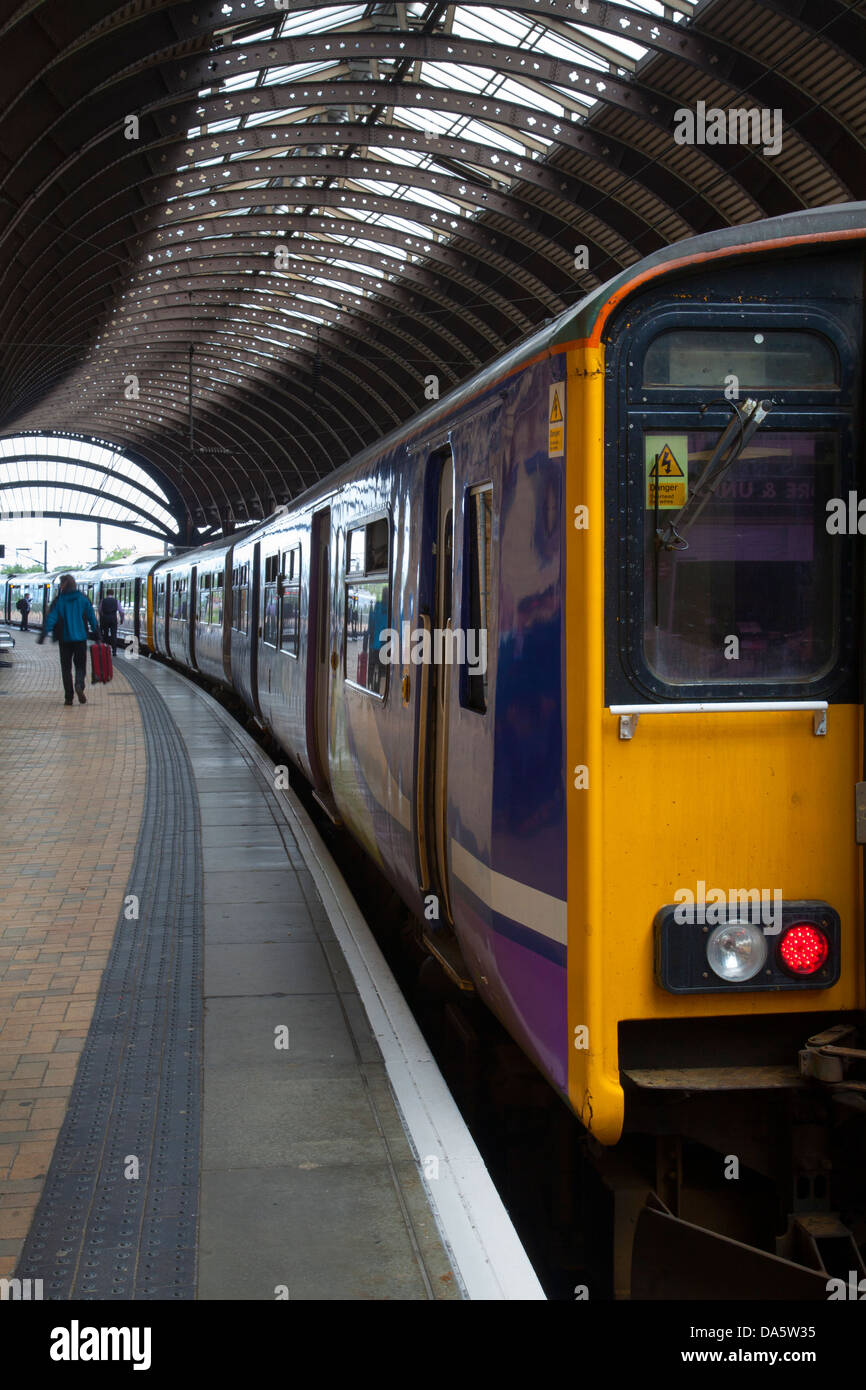 Les navetteurs en attente pour le transport ferroviaire sur la plate-forme à la gare la ligne principale dans la ville de York, Yorkshire, Angleterre, Royaume-Uni Banque D'Images