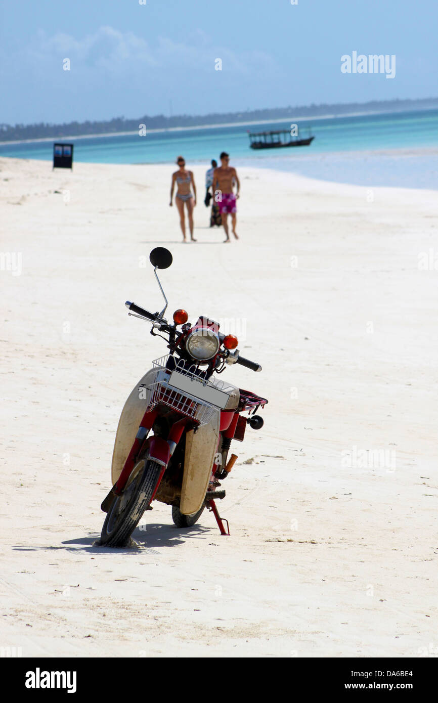 Un scooter garé sur une plage de sable blanc paradise à Zanzibar avec les eaux bleu Banque D'Images