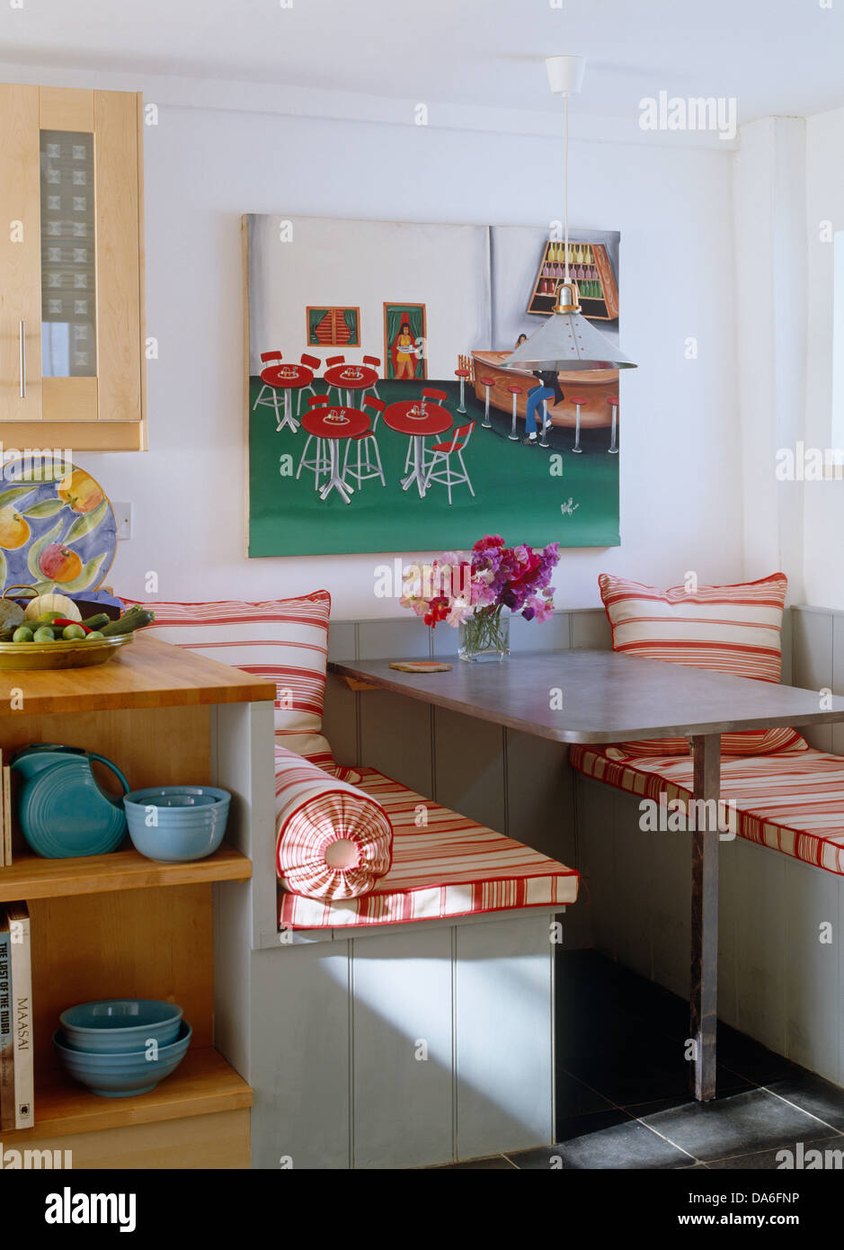 Peinture colorée sur le mur derrière pied fixe métal et construit en coin avec des coussins à rayures rouge en coin de cuisine de campagne Banque D'Images