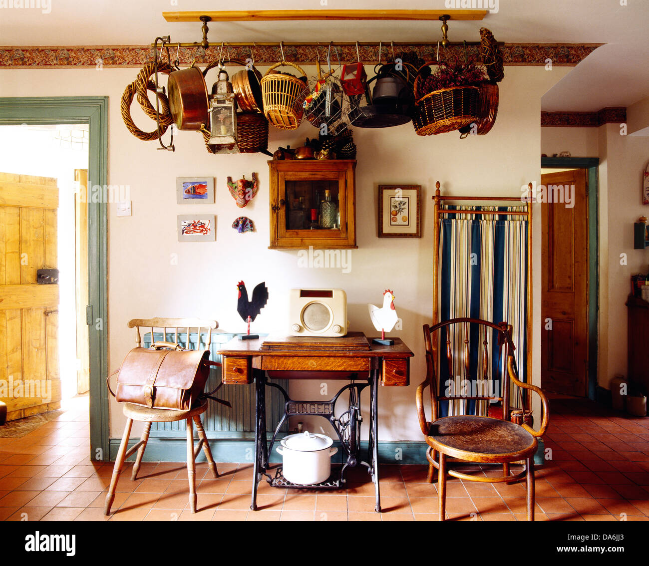 Sur Radio vieille machine à coudre table entre meubles anciens dans un style campagnard avec lanterne et la collection de paniers sur rack de plafond Banque D'Images