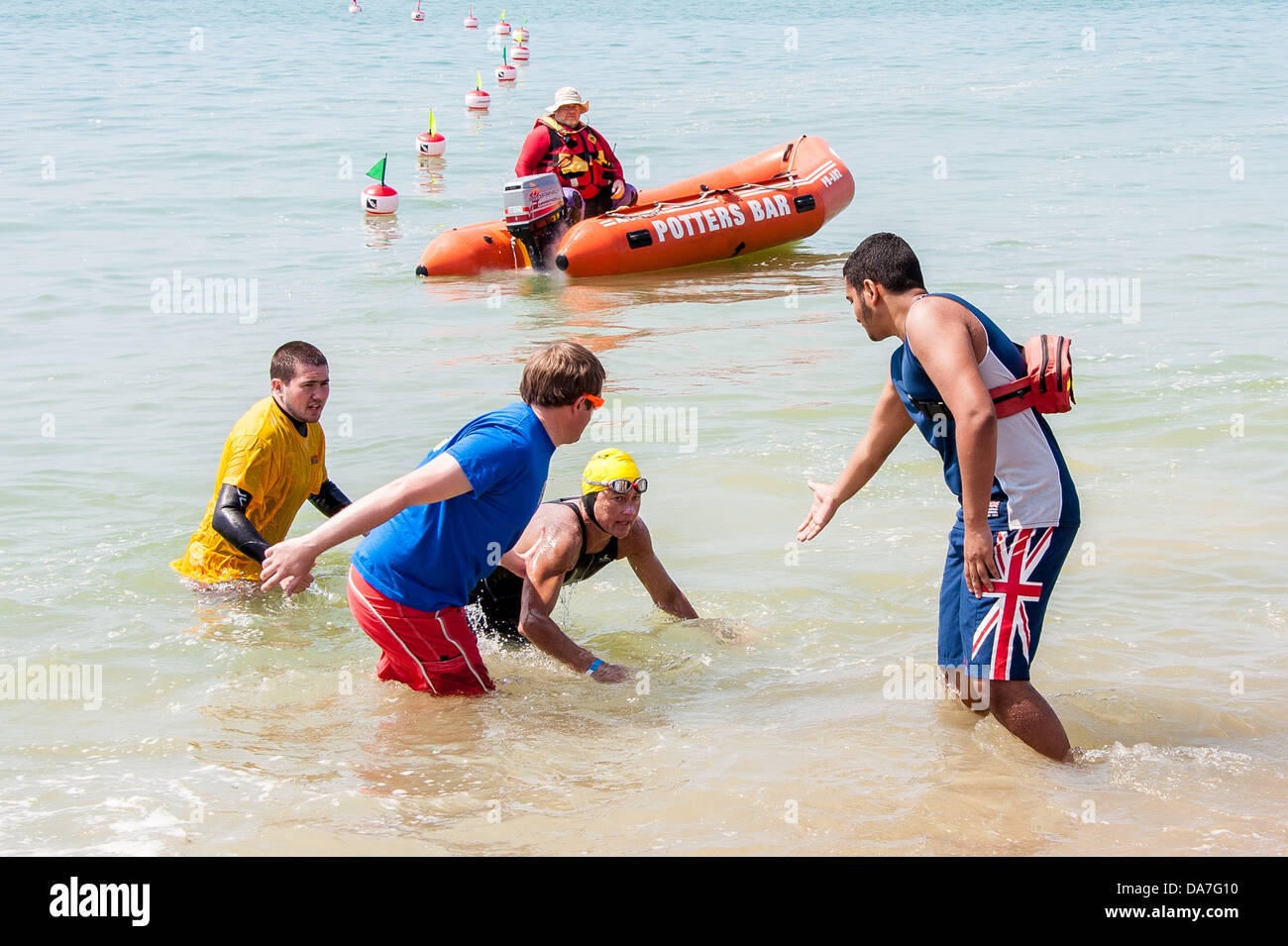 Brighton, UK. 06 juillet 2013. L'hypothermie dans le soleil : un candidat à la course de natation longue distance est assisté dans l'eau après avoir été secouru. Malgré la chaleur du soleil, la température de l'eau peut provoquer l'hypothermie pour longue distance. swimers Pagayez autour du Pier Beach Festival, Brighton, le 6 juillet 2013 Crédit photo : Julia Claxton/Alamy Live News Banque D'Images