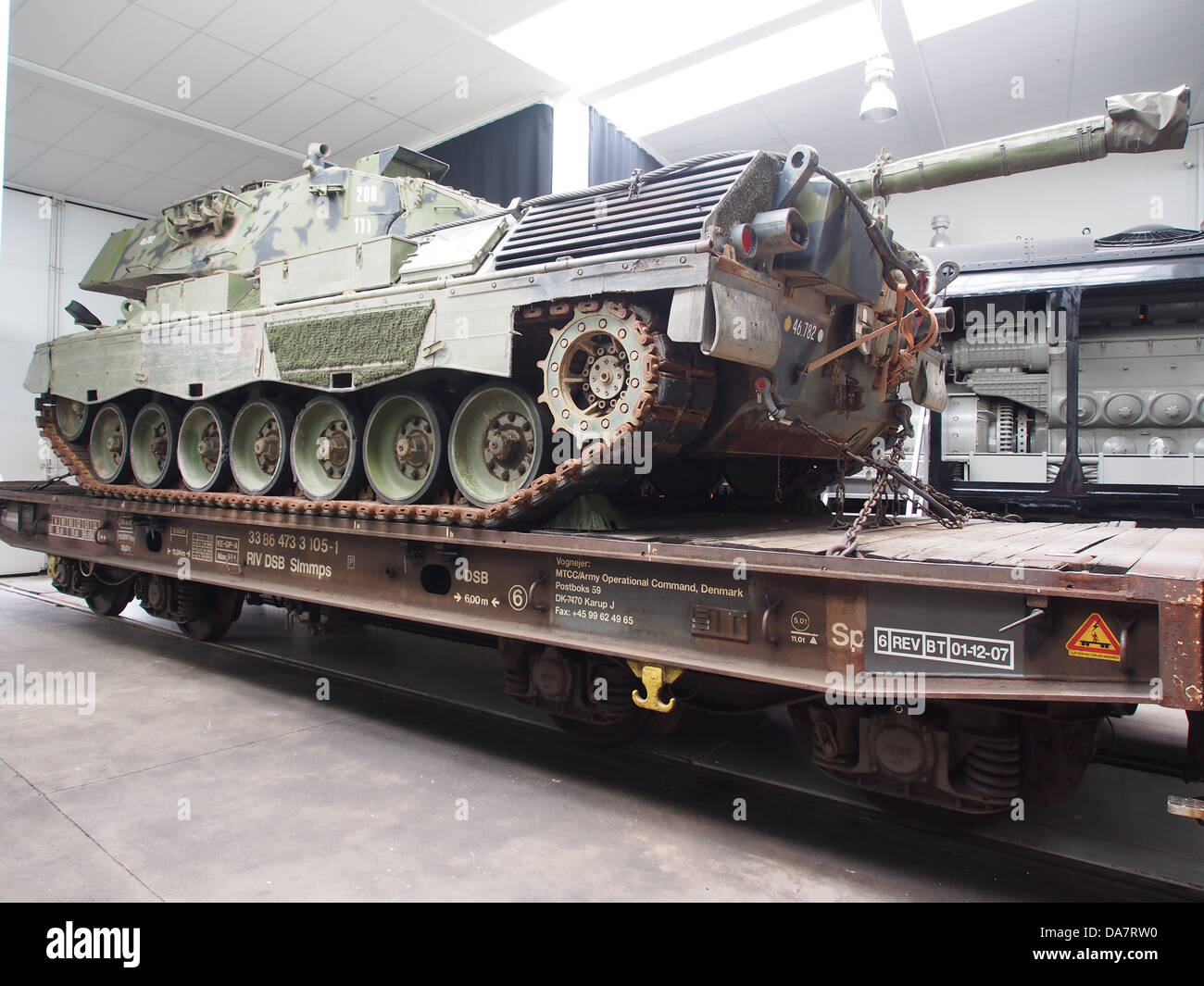 Un wagon à plateau DSB 33 86 473 3 105-1 transporte un char Leopard, mettant en valeur la logistique militaire et les capacités de transport. Le véhicule est utilisé pour déplacer efficacement du matériel militaire lourd sur divers terrains. Banque D'Images