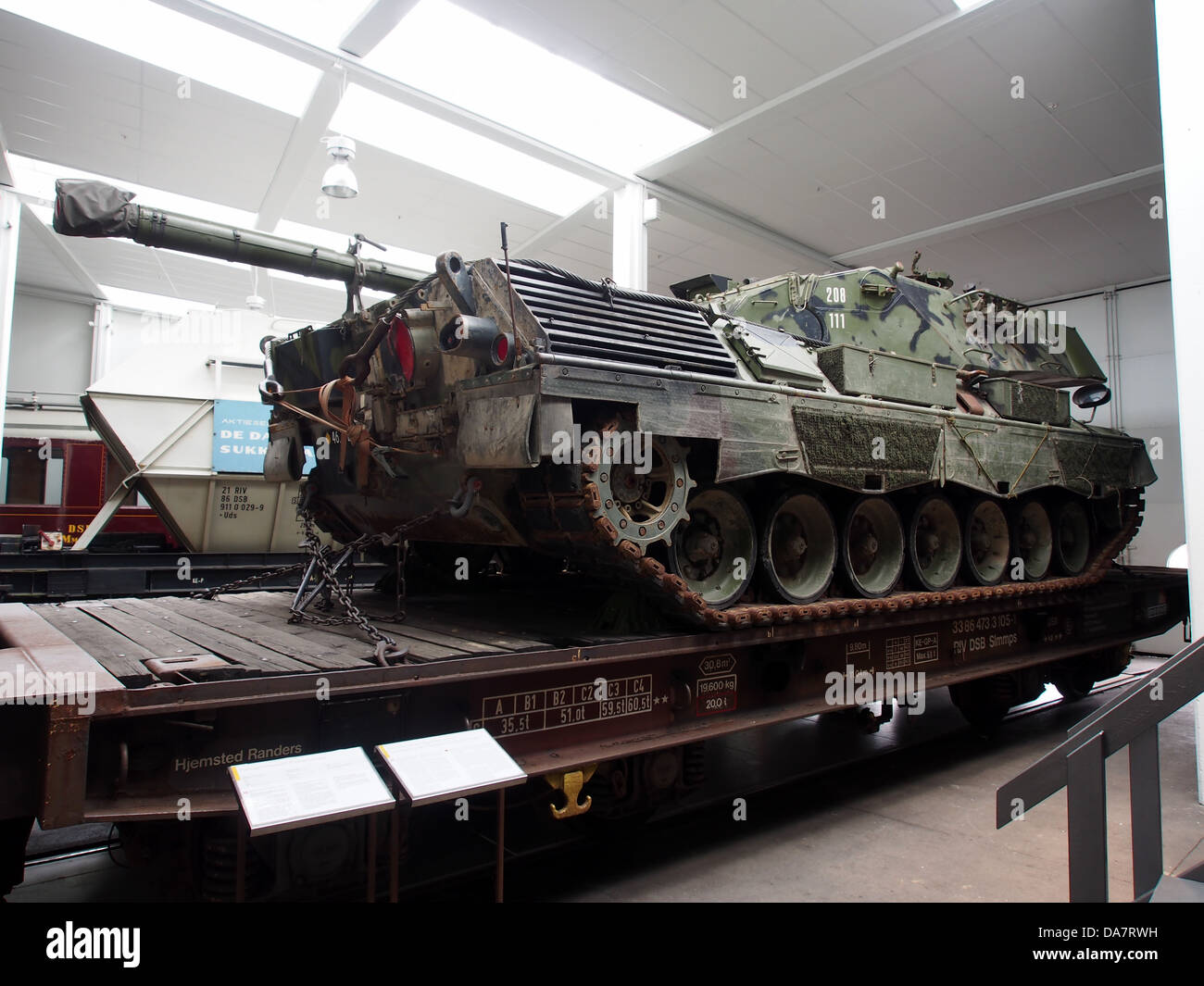 L'image montre un wagon à plateau (DSB 33 86 473 3 105-1) transportant un char Leopard. Cette configuration est utilisée pour le transport de matériel militaire, illustrant la logistique et les méthodes de transport employées pour les véhicules militaires lourds comme le char Leopard. Banque D'Images