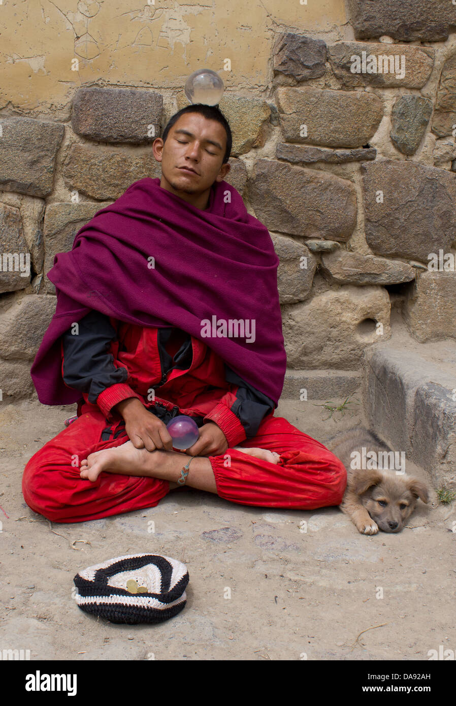 Portrait d'un moine bouddhiste avec dog sitting cross legged contre le rocher,Pérou,Ollantaytambo Banque D'Images