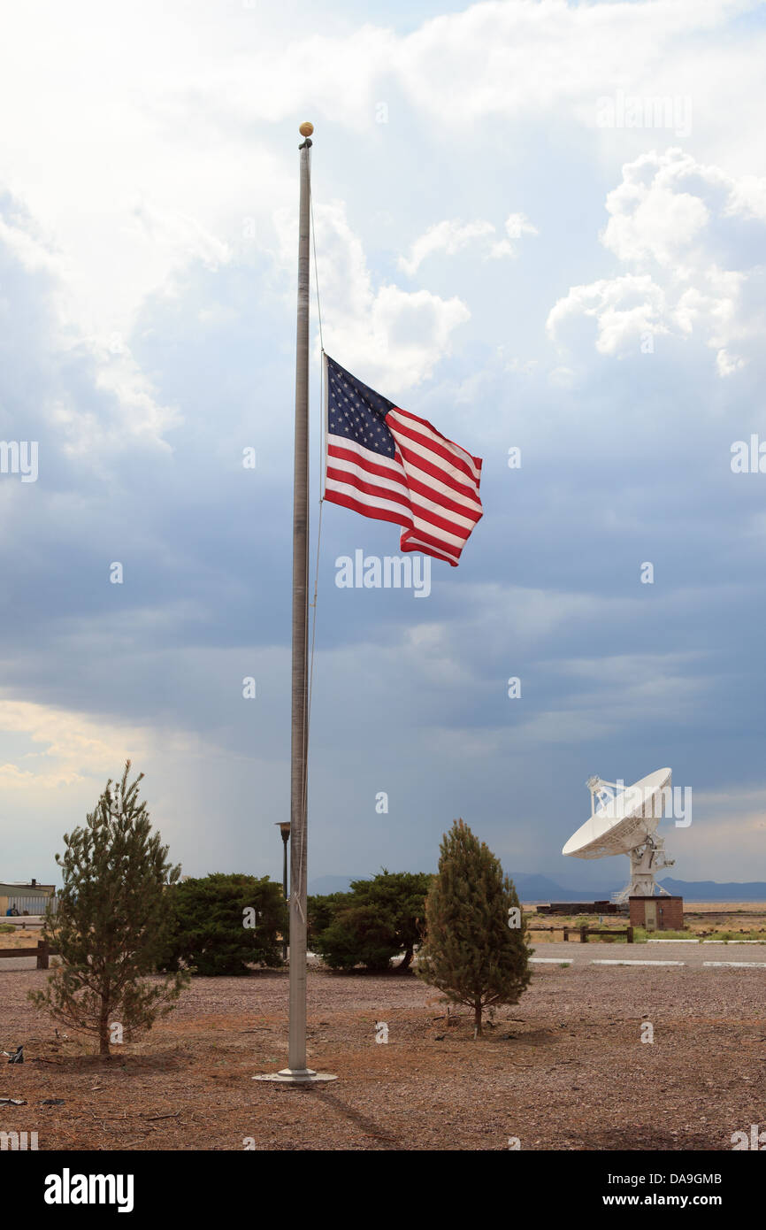 Drapeau américain en berne en premier plan avec une grande antenne satellite en arrière-plan de cette photo au Very Large Array, NM. Banque D'Images