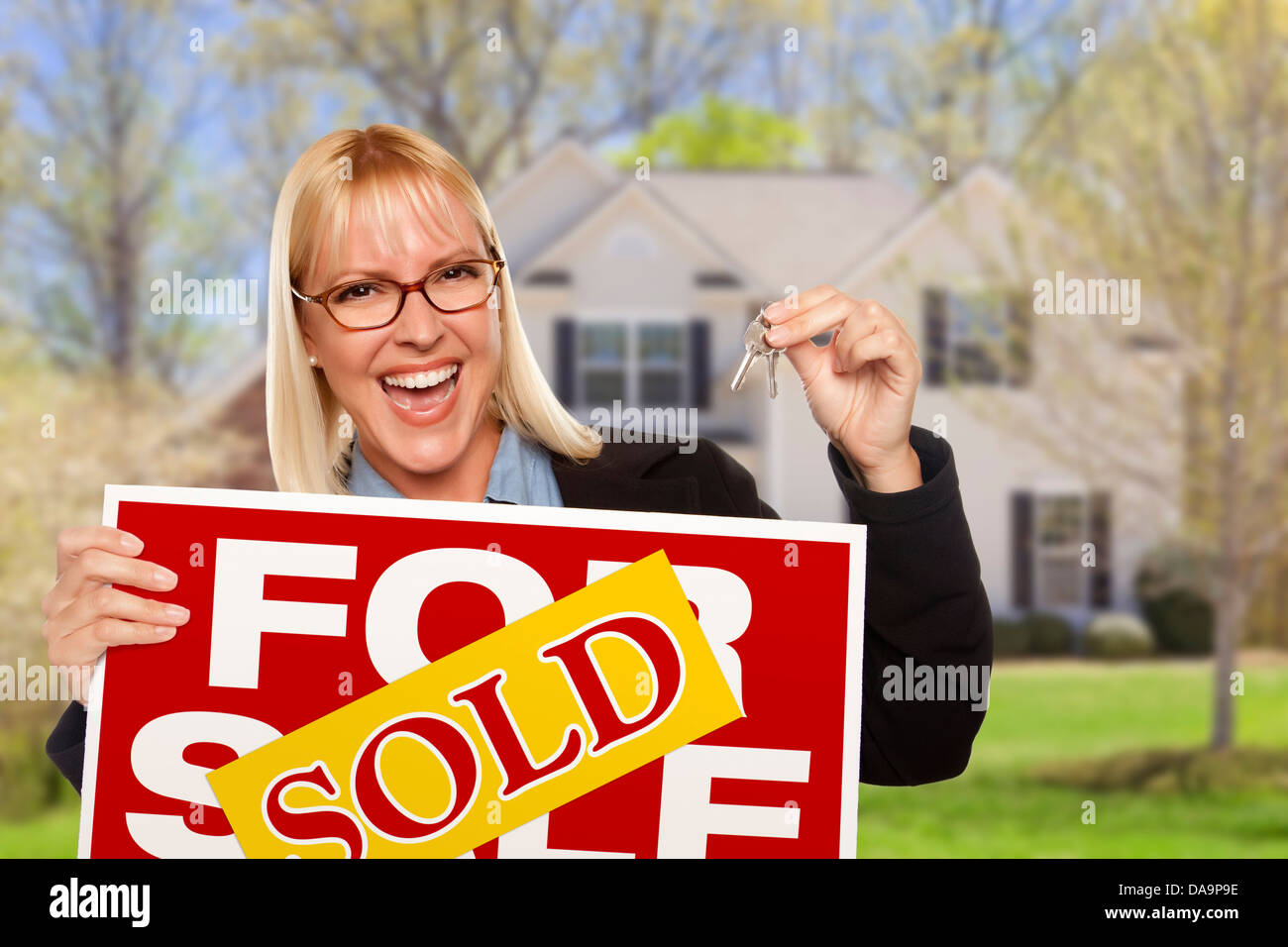Happy Young Woman with vendus en vente enseigne immobilière et les touches en face de la maison. Banque D'Images