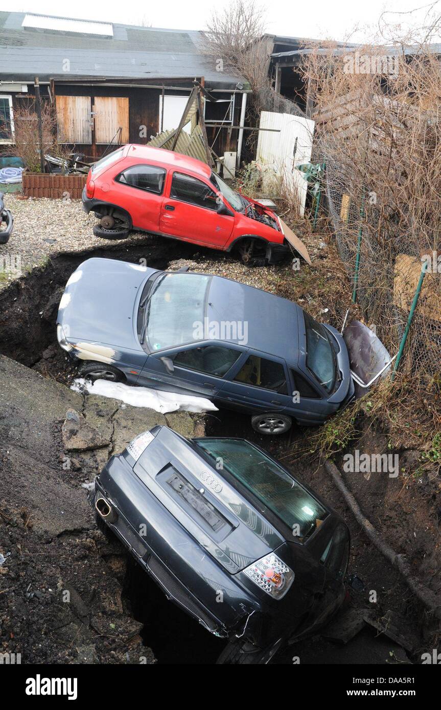 Trois voitures se trouvent dans un trou sur un atelier de réparation automobile's lot à Essen, Allemagne, 09 janvier 2011. L'atelier de réparation automobile se trouve sur un ancien domaine de la mine, selon les déclarations de la police, cependant il n'est pas clair si les huit mètres de profondeur, 9 mètre de large trou a été causée par les activités minières ou de fonte. Photo : KDF-TV/STEPHAN WITTE Banque D'Images