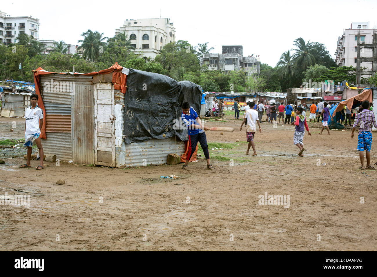 Les pêcheurs de Mumbai et leurs enfants jouer au cricket tandis que le temps de la mousson les arrête la pêche sur la masse des déchets derrière les taudis. Banque D'Images