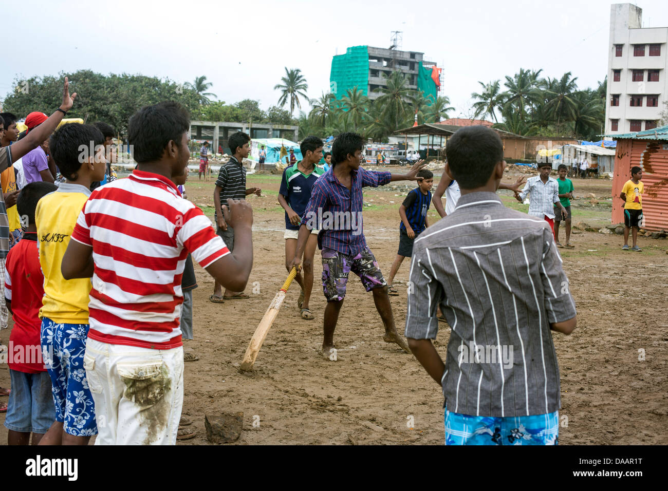 Les pêcheurs de Mumbai et leurs enfants jouer au cricket tandis que le temps de la mousson les arrête la pêche sur la masse des déchets derrière les taudis. Banque D'Images