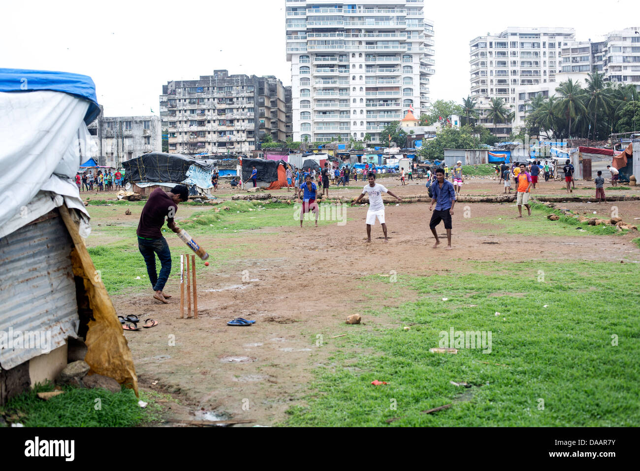Les pêcheurs de Mumbai et leurs enfants jouer au cricket tandis que le temps de la mousson les arrête la pêche sur la masse des déchets derrière les taudis. Banque D'Images