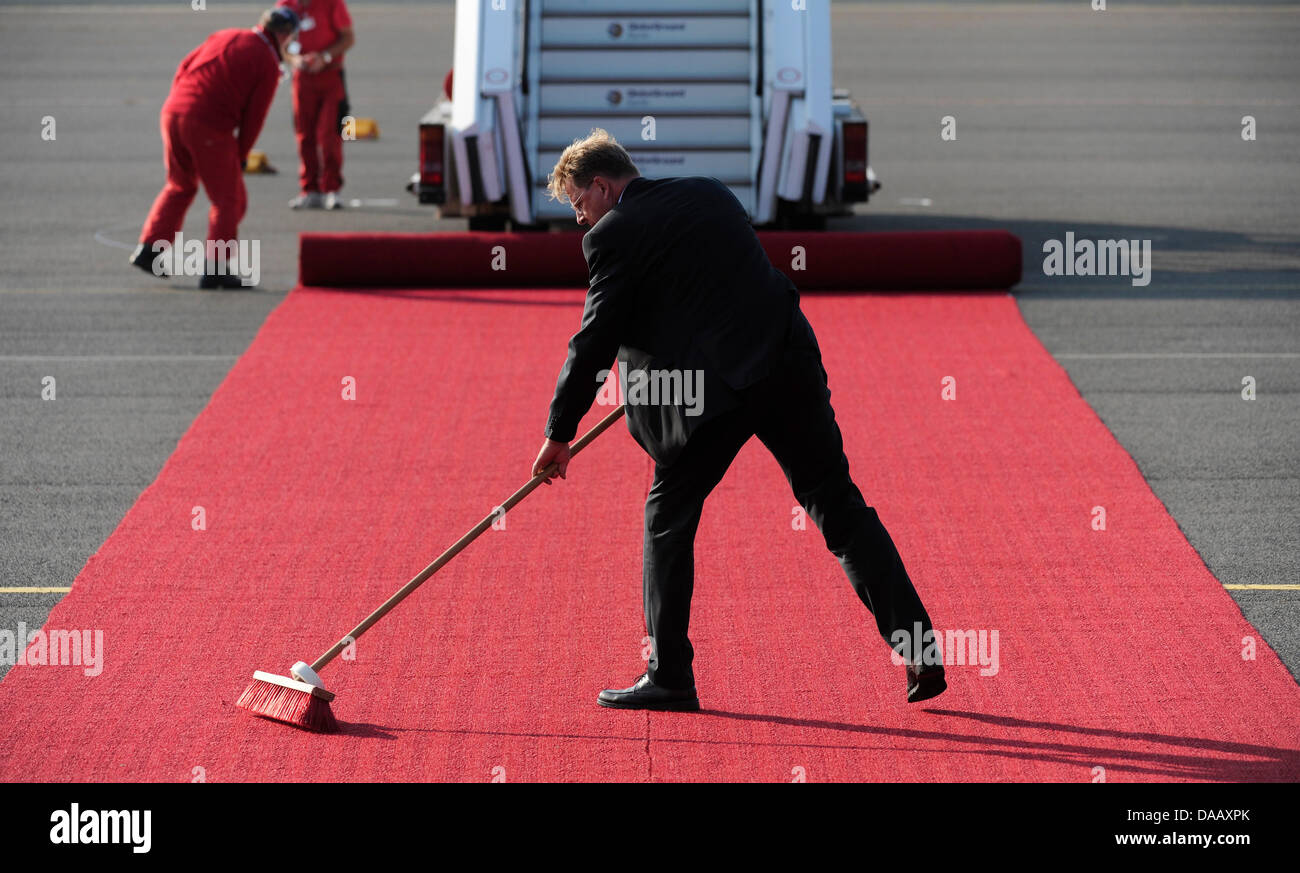 Un homme nettoie le tapis rouge avant l'arrivée du Pape Benoît XVI à l'aéroport de Tegel à Berlin, le 22 septembre 2011. Le chef de l'Église catholique romaine est en visite en Allemagne du 22 au 25 septembre 2011. Photo : Maurizio Gambarini Banque D'Images