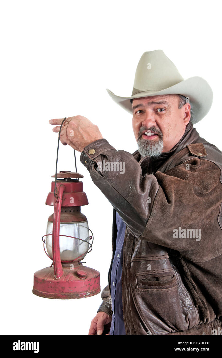 Cowboy mature quitte le poulailler avec une lanterne au kérosène. Isolé sur un fond blanc. Banque D'Images