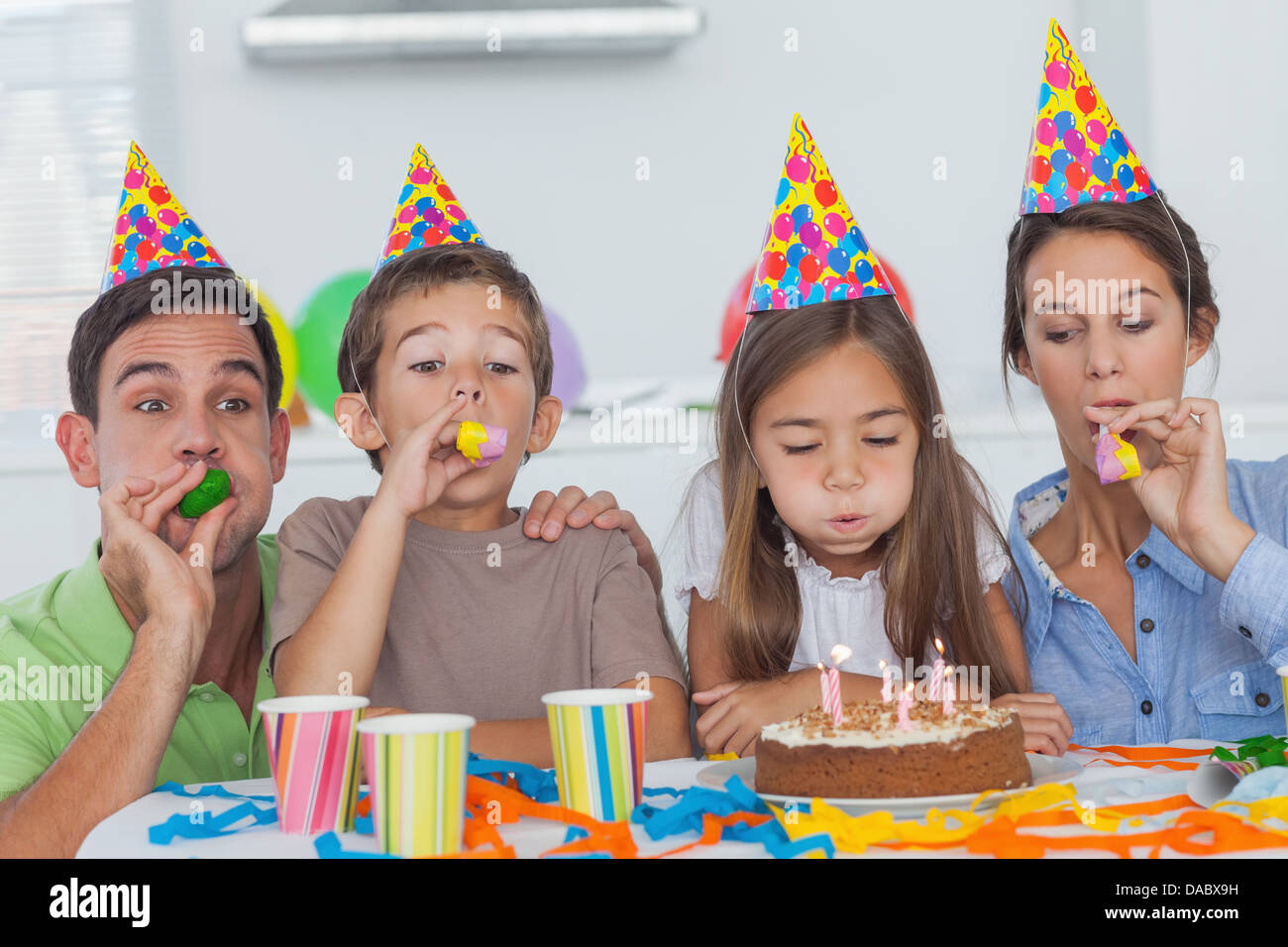 Famille avec party horn celebrating their daughter party Banque D'Images