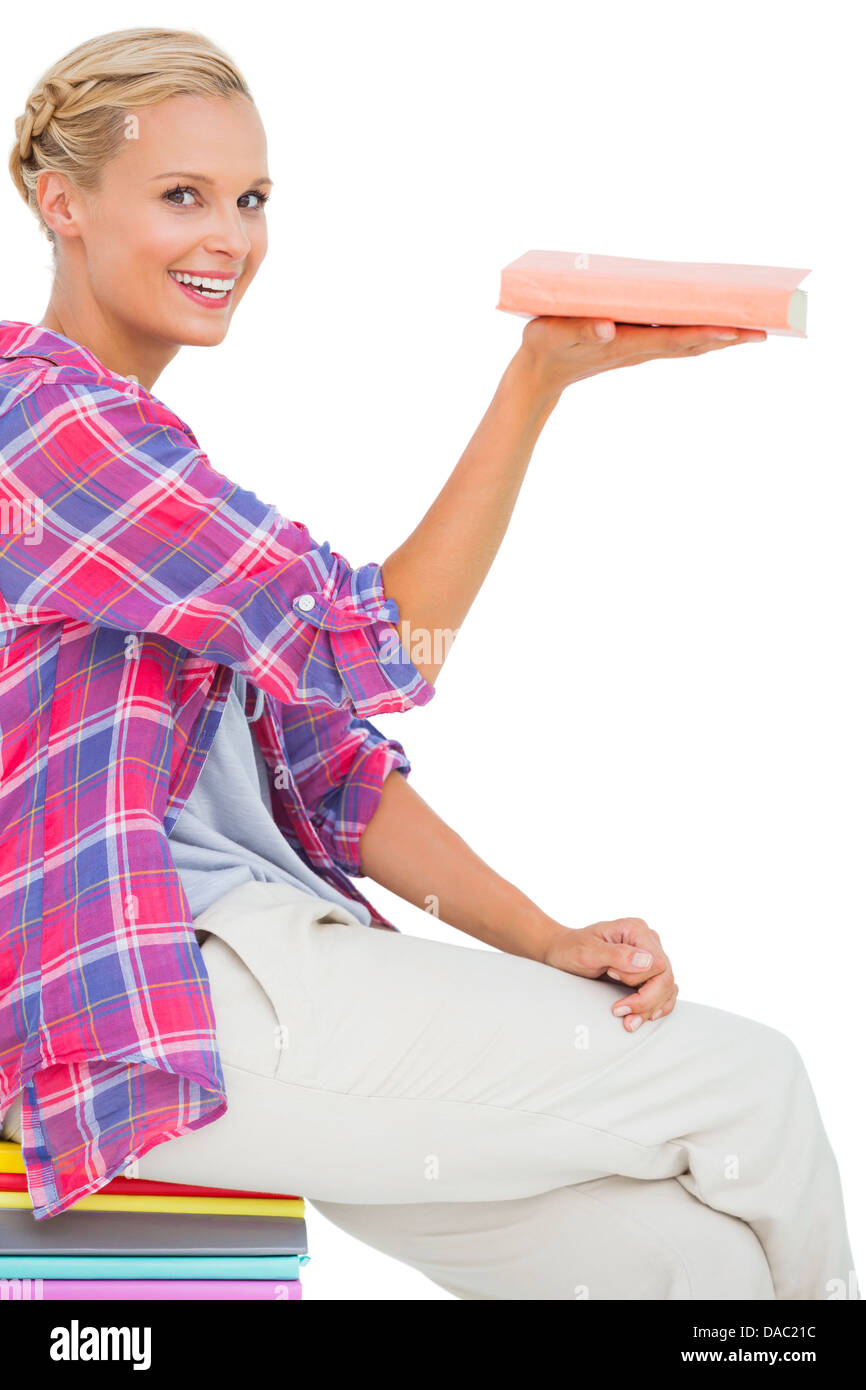 Belle femme montrant un livre et smiling at camera Banque D'Images