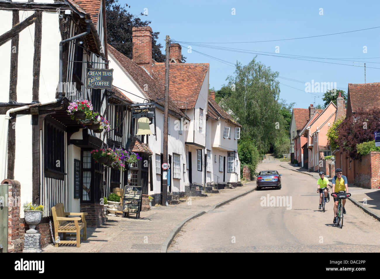 Deux cyclistes à vélo dans les rues de Kersey, considéré comme le village le plus pittoresque dans le Suffolk, Angleterre. Banque D'Images