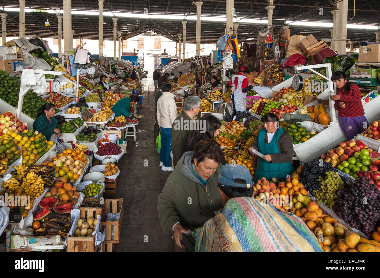 Les vendeurs de légumes fruits femmes Inca boutiques stands de vente qui tend à servir les clients au marché local au centre-ville de Cusco, Pérou. Banque D'Images