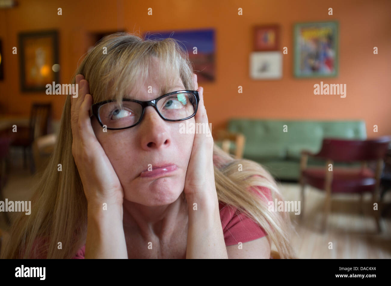 Femme avec les mains sur le côté du visage pour faire une expression stupide. Banque D'Images