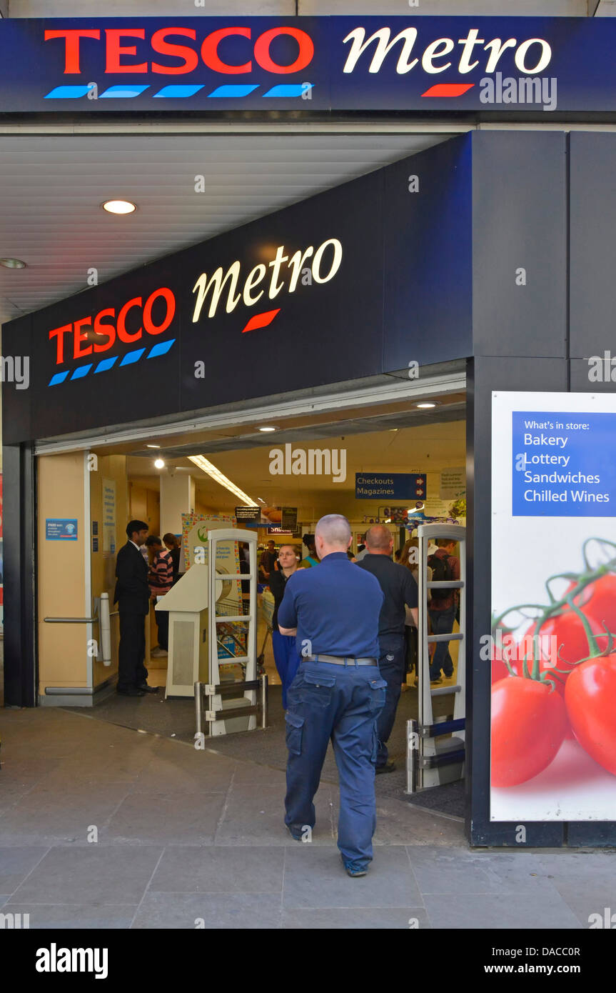 Les gens qui marchent à l'entrée d'achats ci-dessous signe à City de Londres Métro supermarché Tesco business store d'épicerie au détail dans les grands bureaux, England UK Banque D'Images